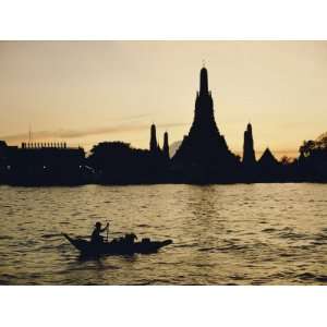  A Man Paddles a Boat Past Wat Arun at Twilight Stretched 